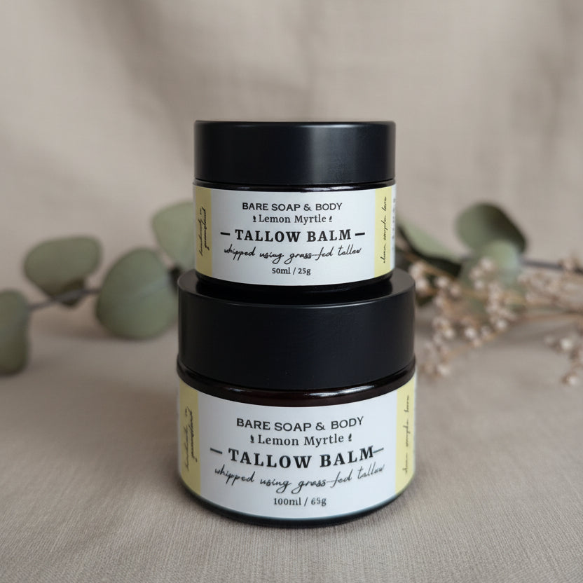 Two small jars of Bare Soap & Body Tallow Balm stacked vertically on a woven wicker surface, with a neutral gray background.