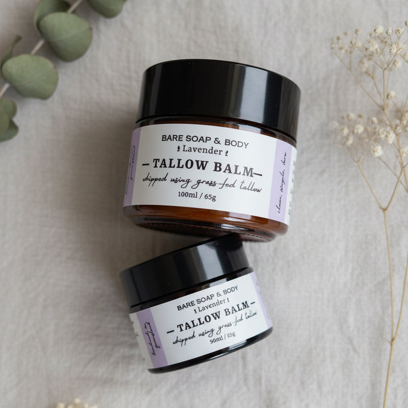 Two jars of Bare Soap & Body Tallow Balm in Lavender scent, stacked vertically on a woven gray textured surface.