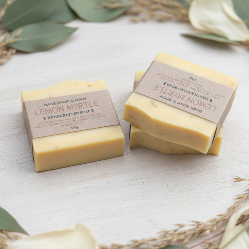Two bars of lemon myrtle tallow soap with labels on a light surface with green leaves.