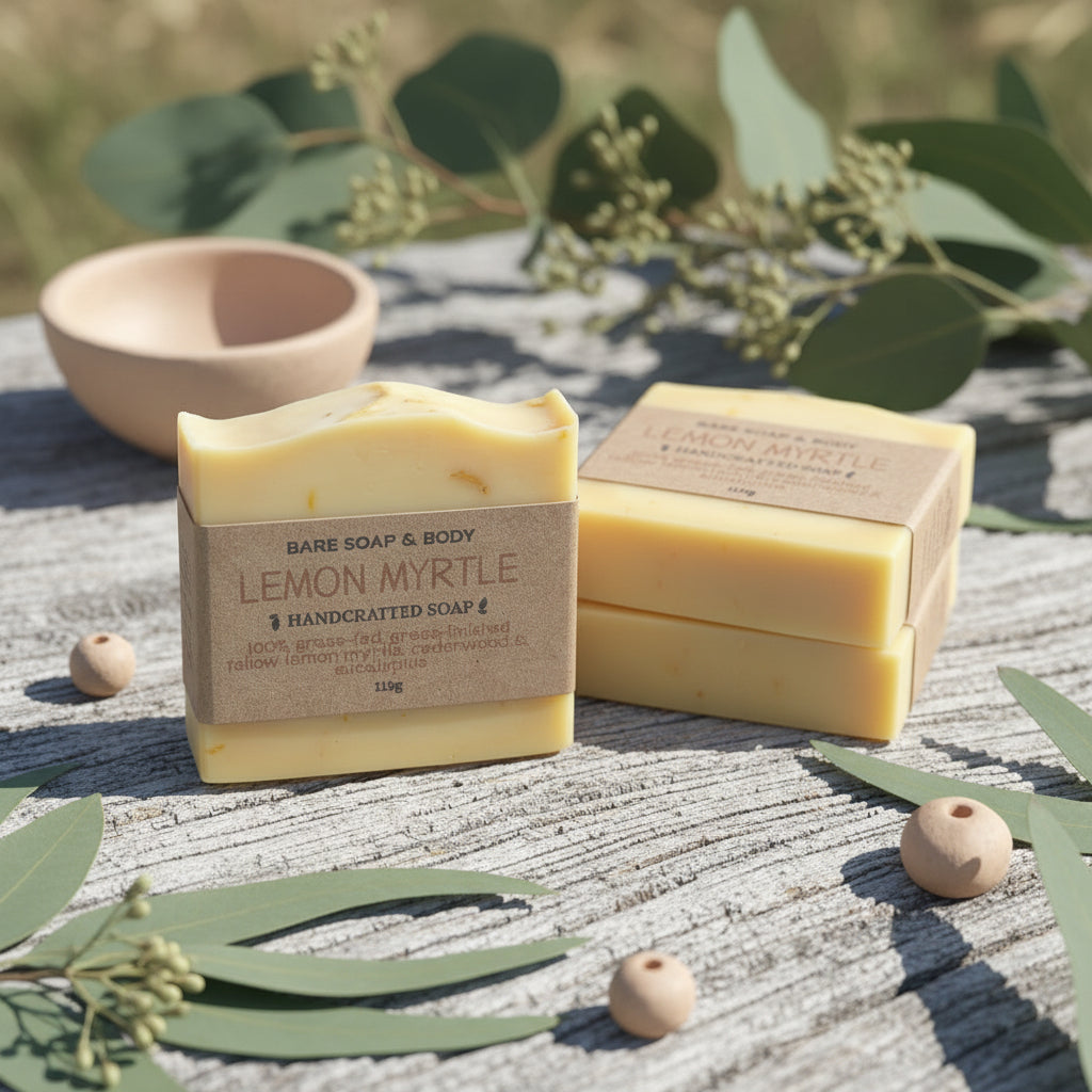 Three tallow bars of lemon myrtle soap on a wooden surface with eucalyptus leaves.