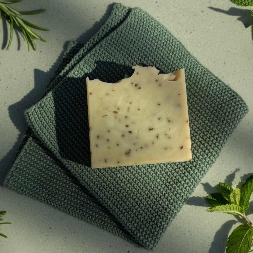 Bar of green clay soap on a green textured cloth 