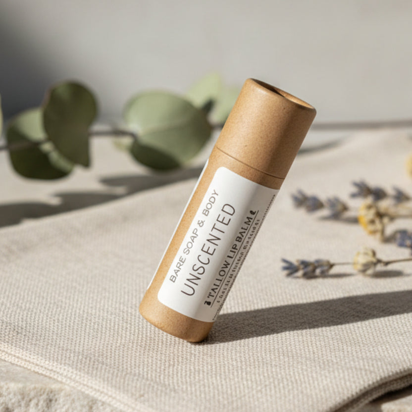 A small cylindrical bare soap & body stick in a brown kraft paper tube with a white label reading 'BARE SOAP & BODY UNSCENTED', placed on a white surface.