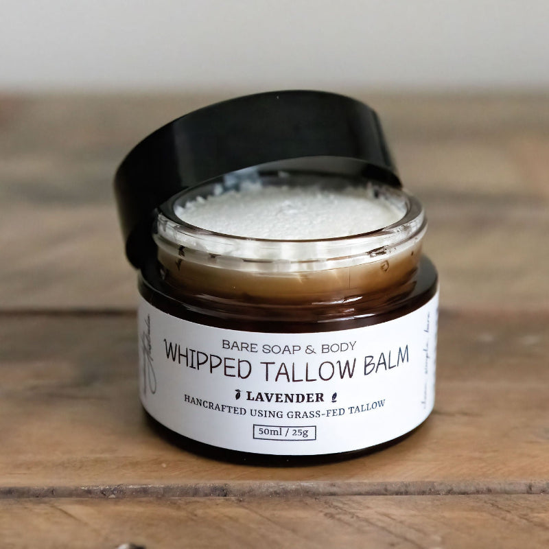 Whipped tallow balm jar with a black lid on a wooden surface
