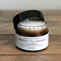 Whipped tallow balm jar with a black lid on a wooden surface