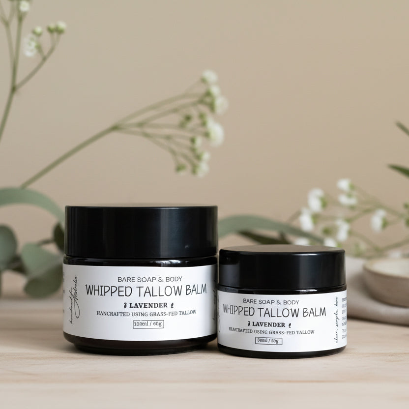 Two jars of Whipped Tallow Balm from Bare Soap & Body on a wooden surface with a beige background.