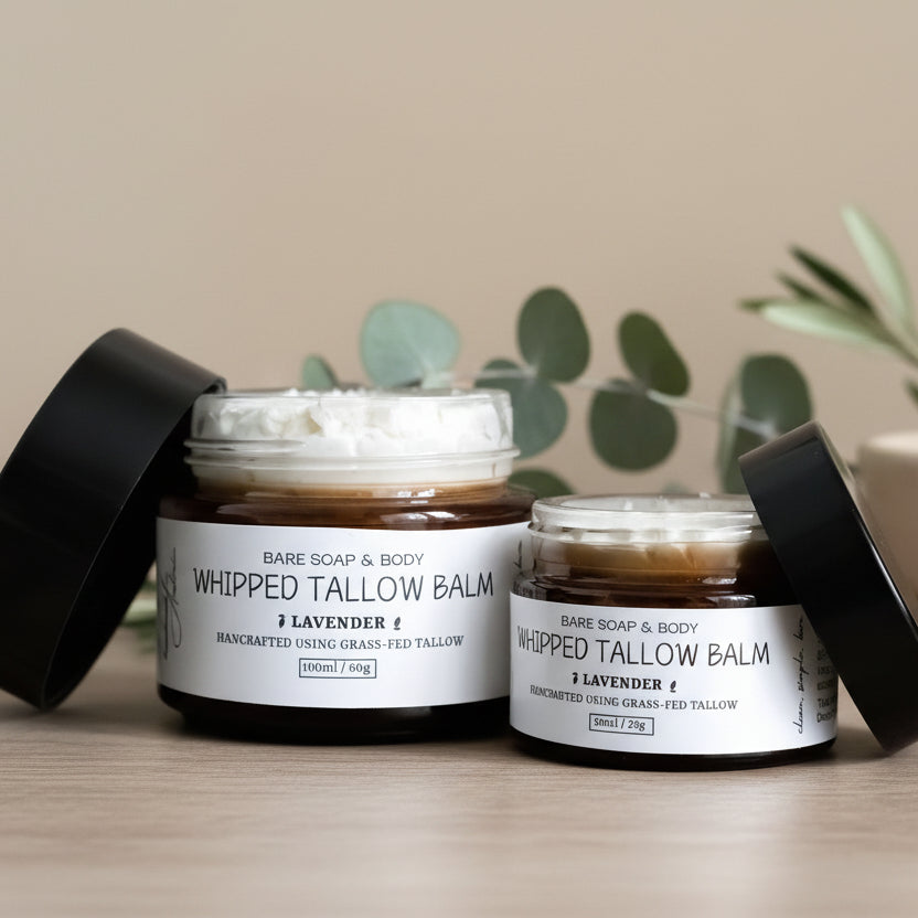 Two jars of Bare Soap & Body Whipped Tallow Balm on a wooden surface with a plant in the background.