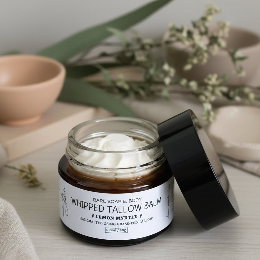Jar of whipped tallow balm with a black lid on a wooden surface