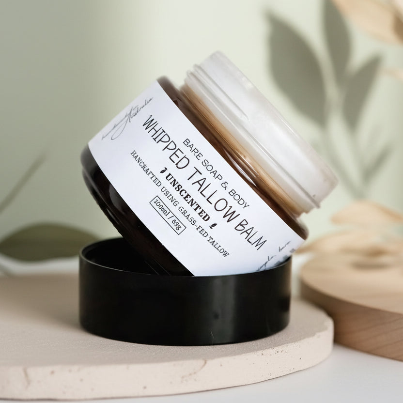 Whipped tallow balm jar with label and black lid on a wooden surface