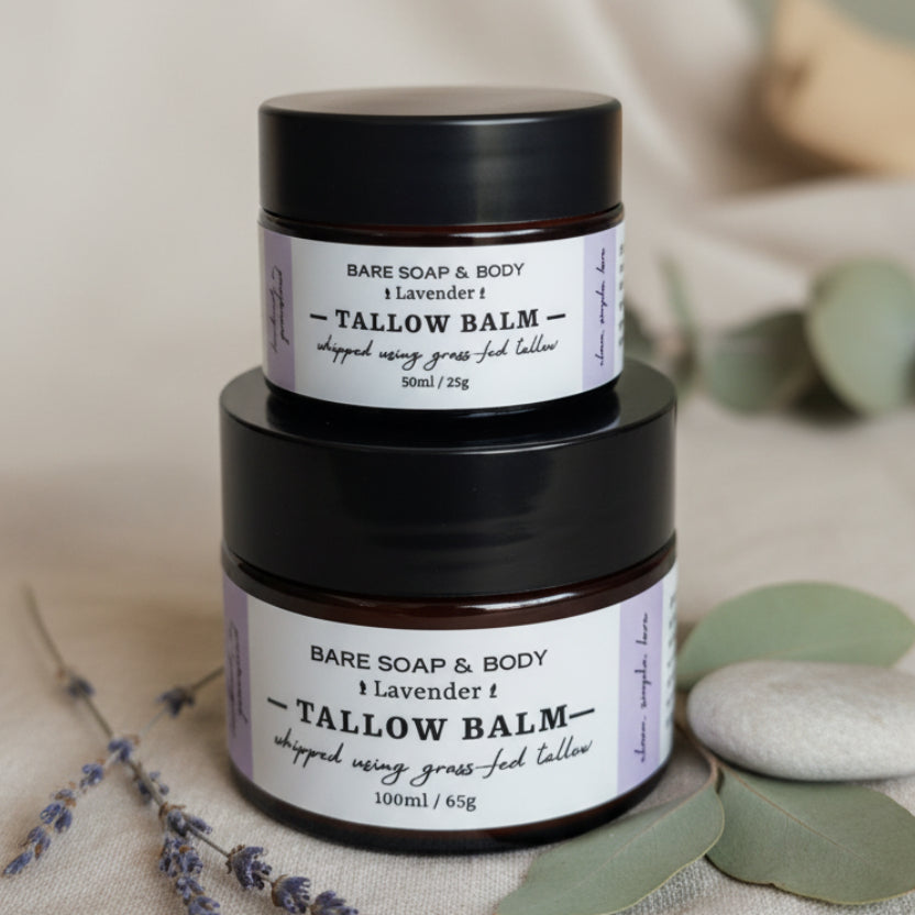 Two small jars of Bare Soap & Body Tallow Balm in lavender scent, stacked on a dark woven wicker surface.